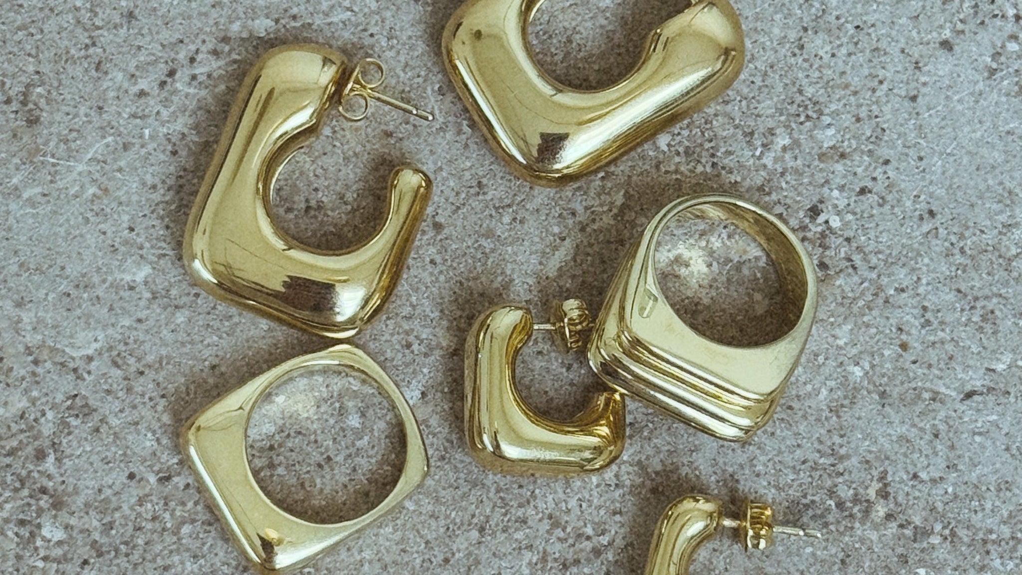 Gold hoop earrings on a textured gray surface